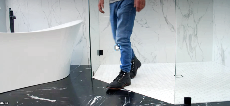 Freestanding tub with floor faucet on black marble floor and white porcelain walls